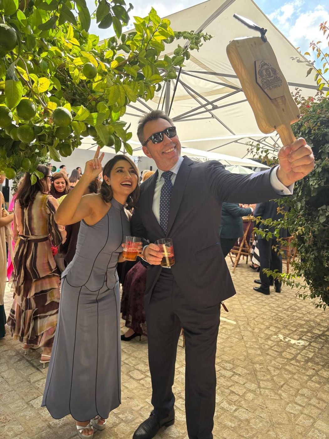 Dos invitados de boda haciéndose una foto con el fotomatón selfie, una pala de madera con el logotipo de Fotomatón El Puerto grabado