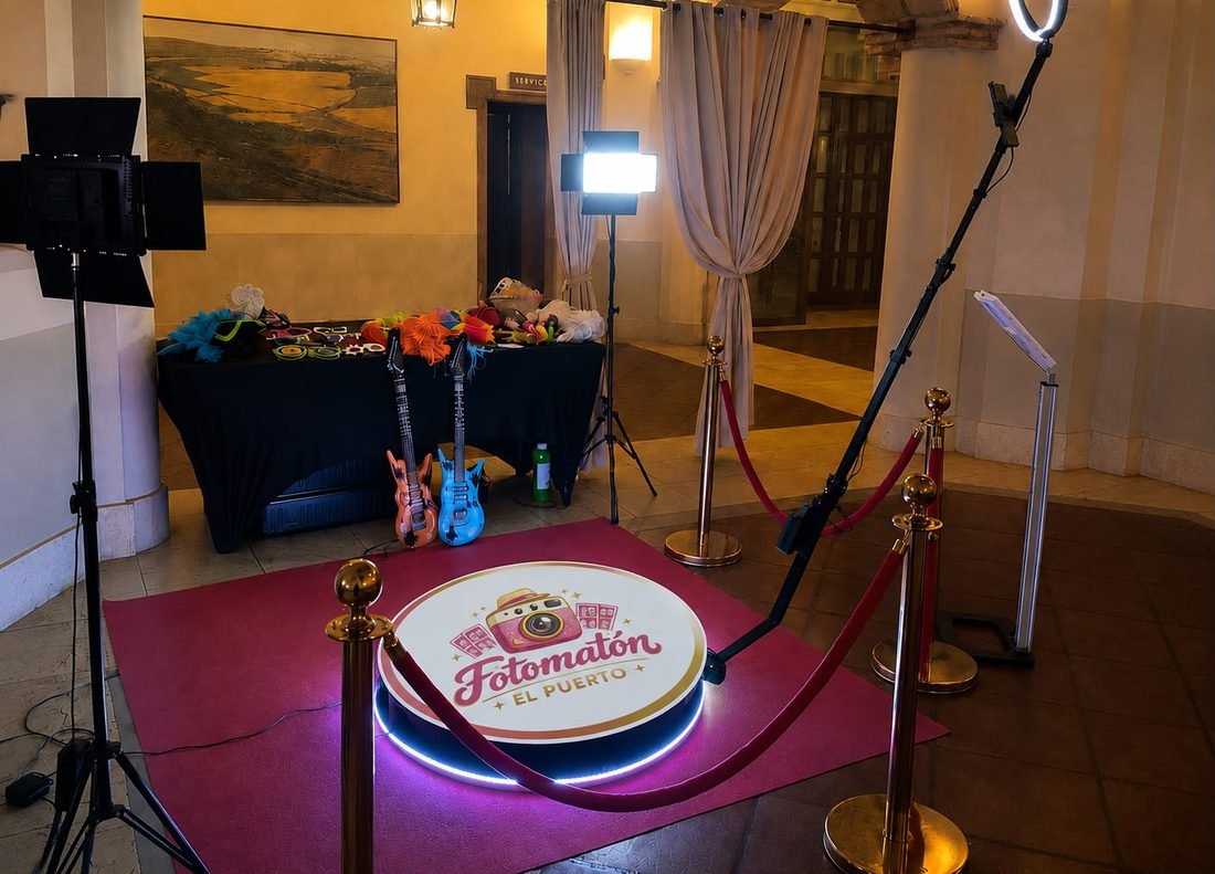 Plataforma giratoria 360° con el logotipo de Fotomatón El Puerto iluminado, aro de luz y mesa de atrezzo, montada en un salón